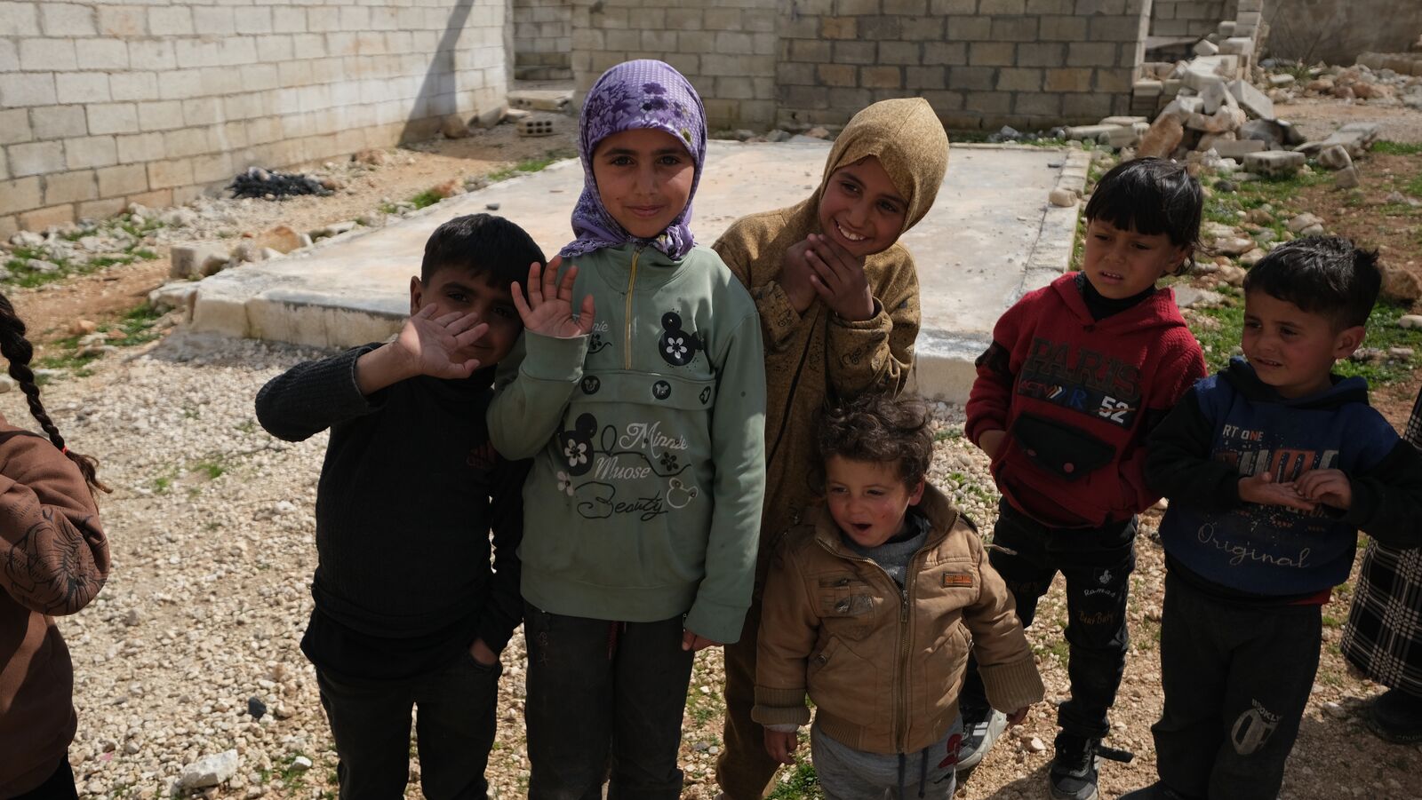 Children waving during a water distribution in a camp