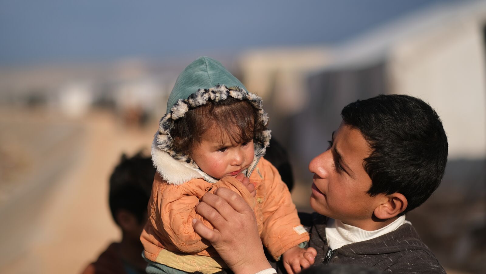 A boy holding his little sister in a camp