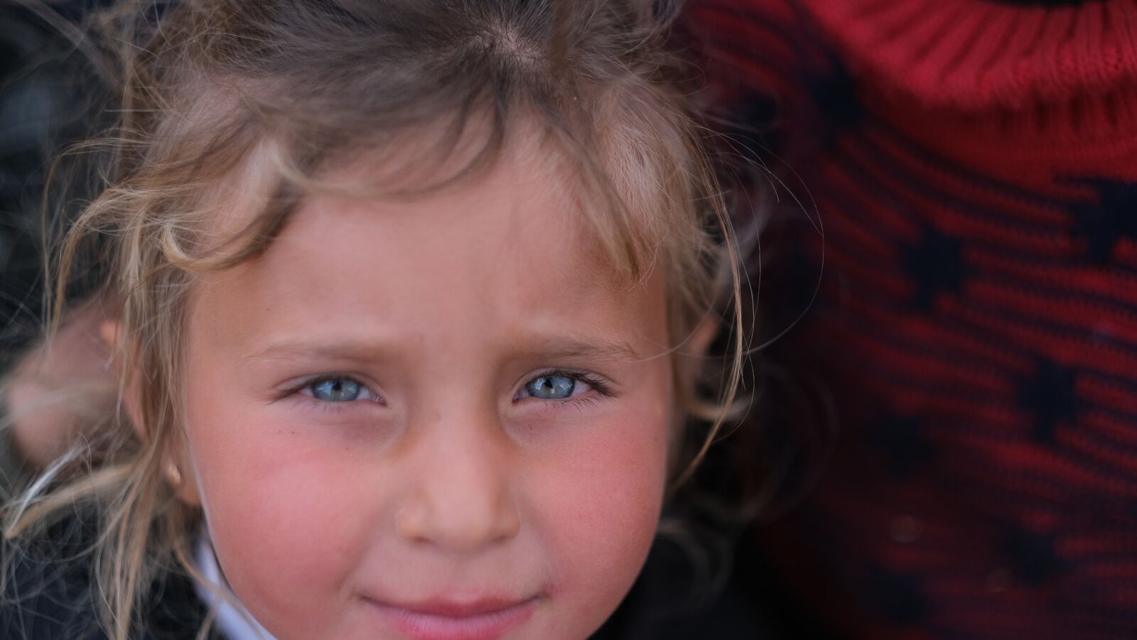 A blue-eyed girl smiling in a camp